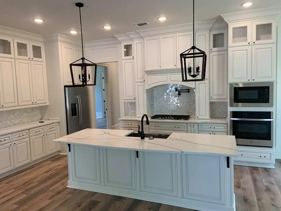Kitchen countertops in Ocean Springs: white island with gray-veined quartz top, undermount sink, lantern pendants and white cabinets