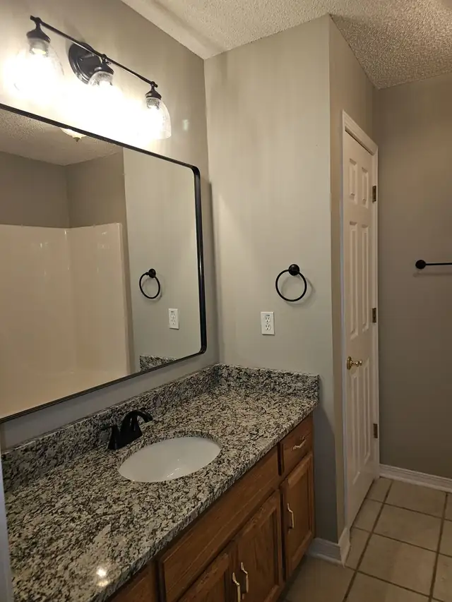 Bathroom vanity with speckled black, white and gray granite top, undermount sink and black-framed mirror