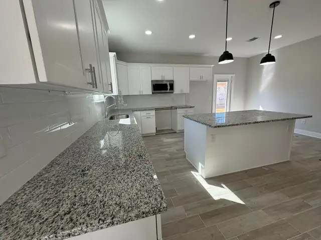 Open kitchen with gray and white speckled granite perimeter counters and a matching granite island
